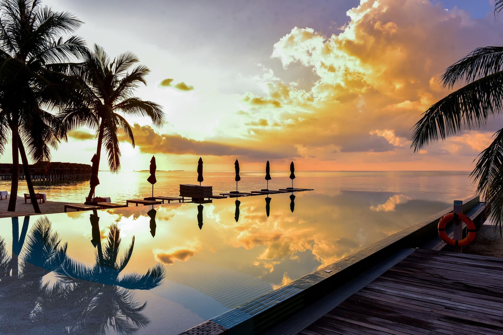 Sun setting over a tropical resort infinity pool