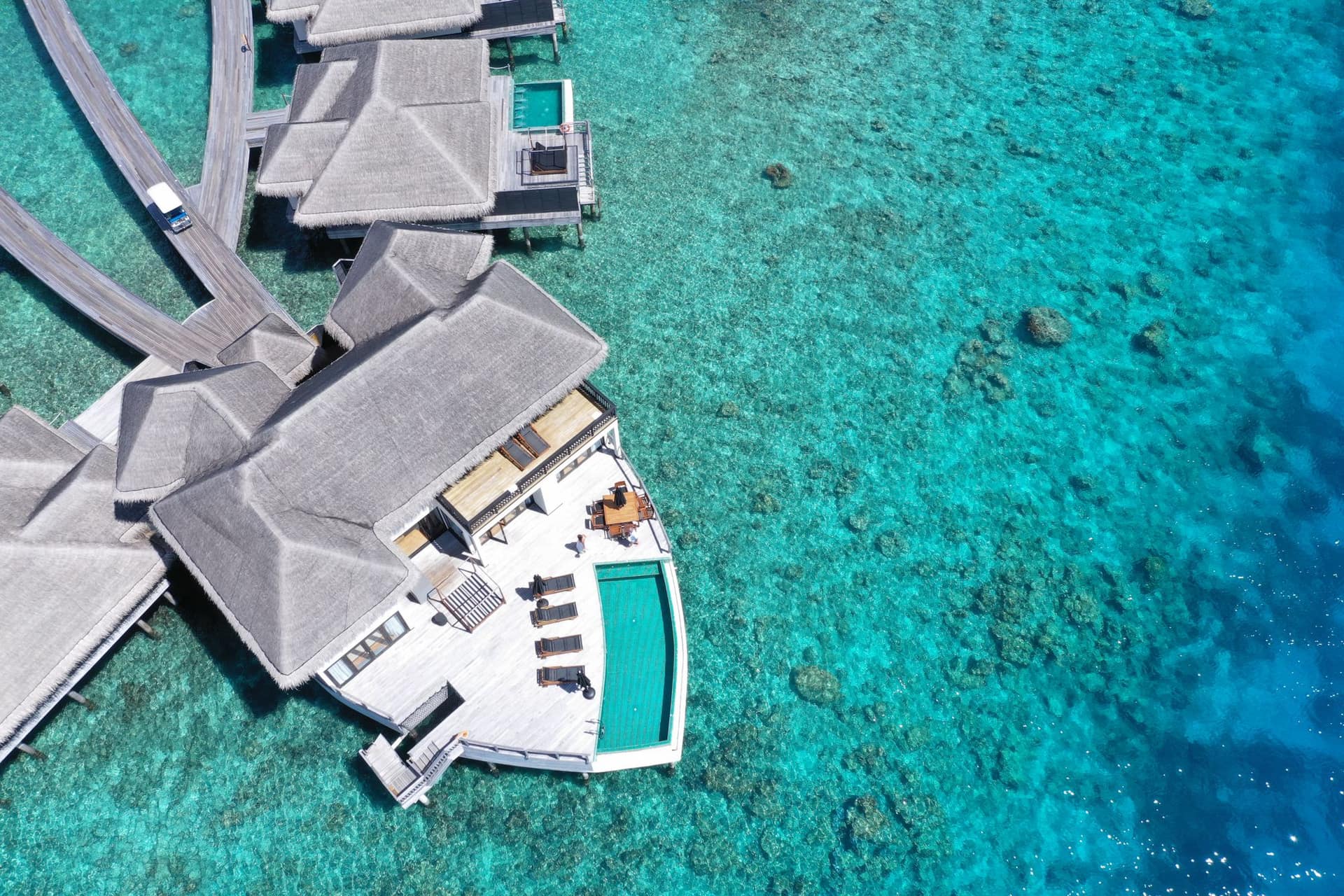 Aerial view of a luxury overwater villa in clear blue water